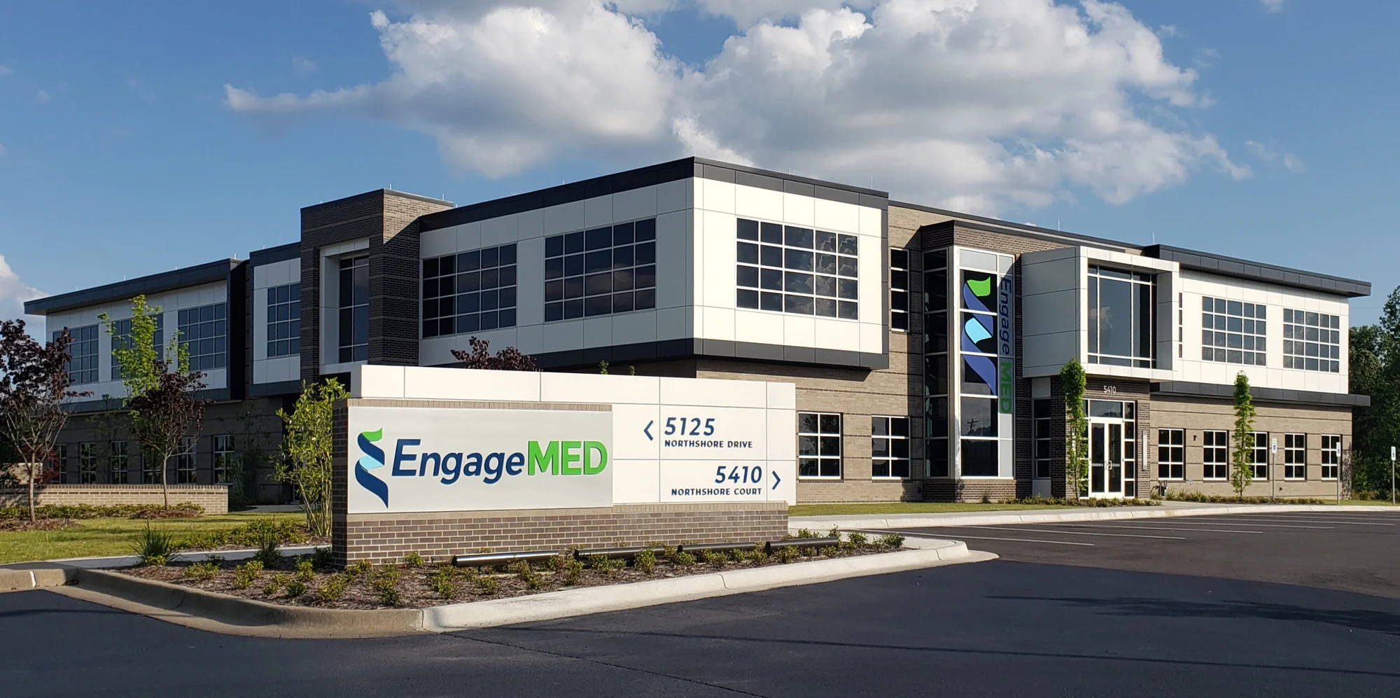 A two-story office building with large windows and a sign in front reading EngageMED.